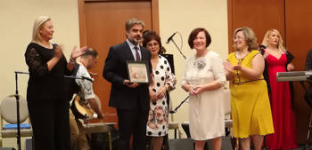 A man holds an award while people around him clap